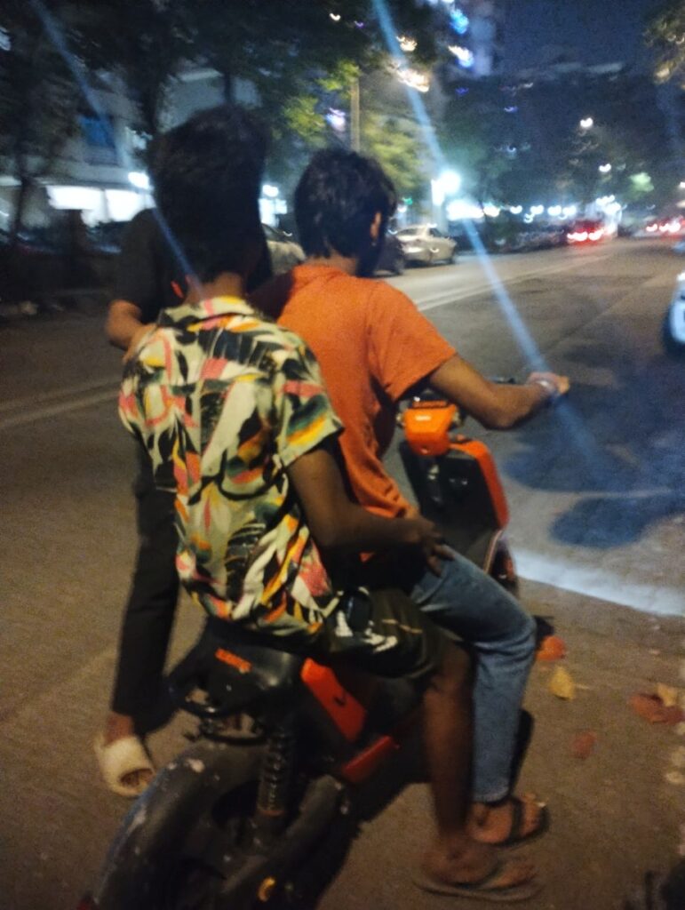 Two guys trying to fit on one scooter. (Photo: Gandhrava Purohit for BESTpedia)